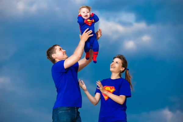 Happy family, mom, dad and little son in costume Superman having