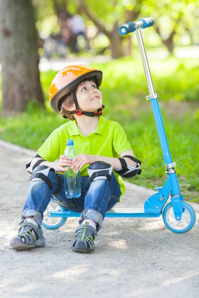 Young boy with  bottle   on kick scooter