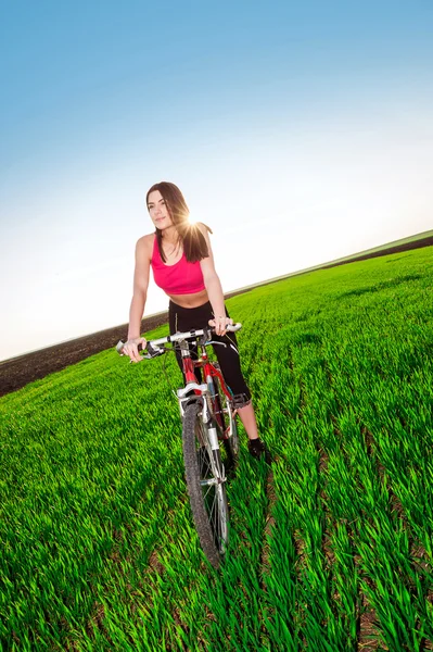 Woman biking in sunset on green grass