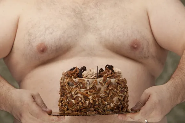 Shirtless overweight man holding a cake in his hands