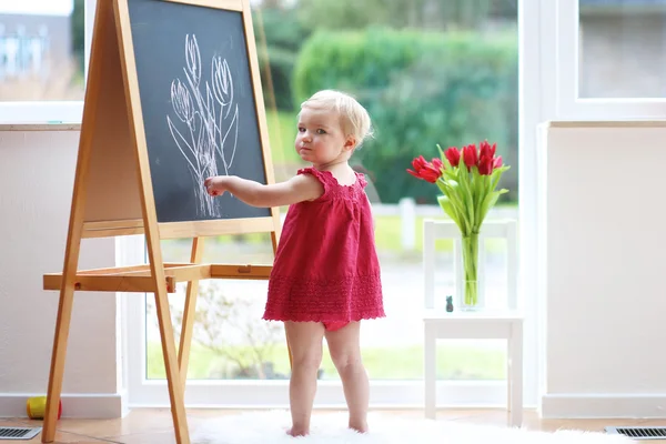 Girl drawing tulips with chalk on black board