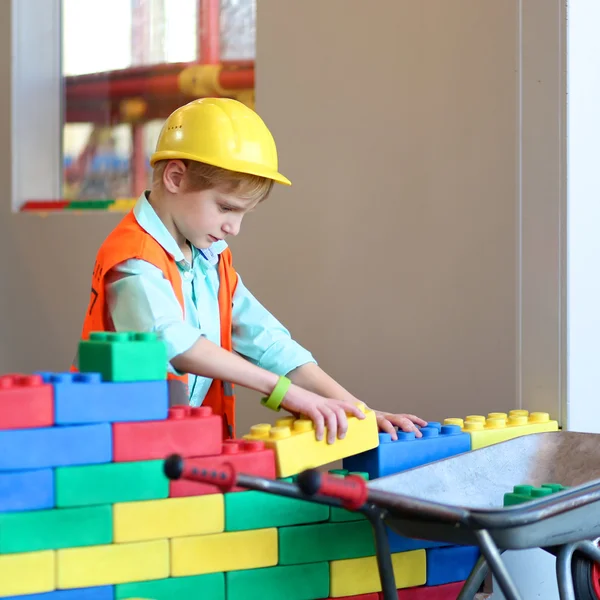 Boy building a house with big plastic construction bricks