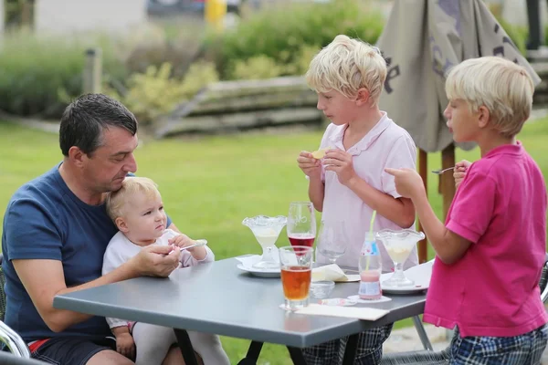 Father with sons and daughter in cafe eating ice cream