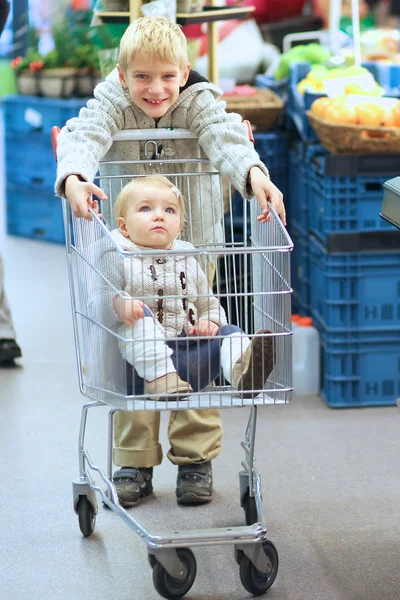 Boy drives shopping cart with his sister
