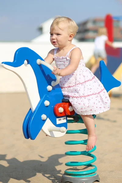 Baby girl rocking on a spring blue dolphin