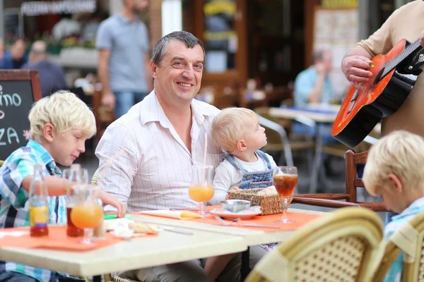 Family in cafe on summer terrace in a center of busy city street