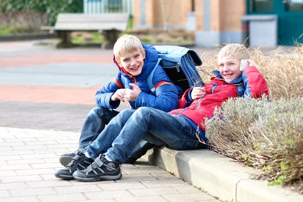 Twin brothers sitting outside of the school