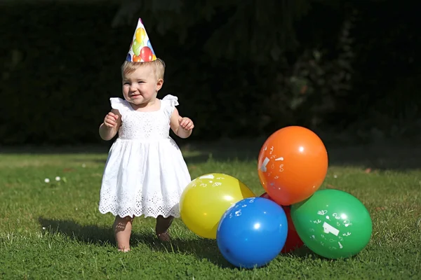 Baby girl next to colorful balloons