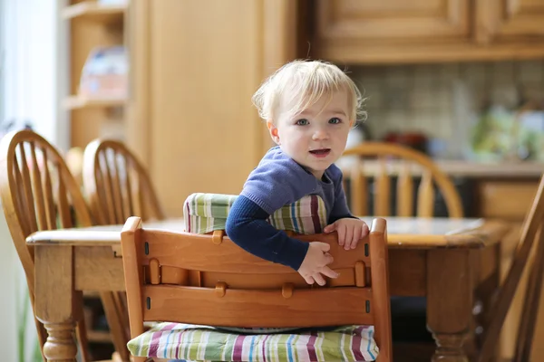 Girl sitting in the kitchen in high chair