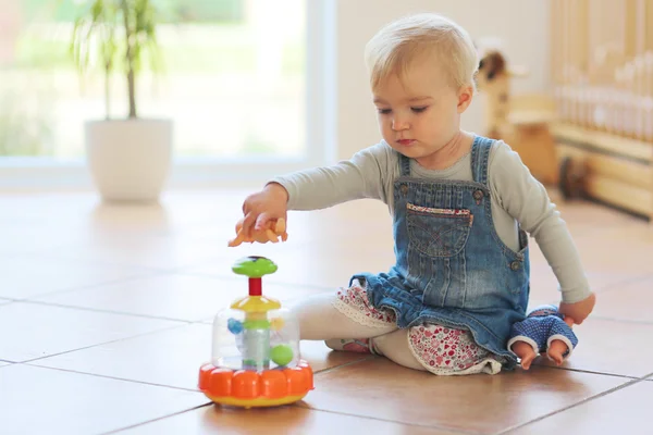 Baby girl plays with toys on floor