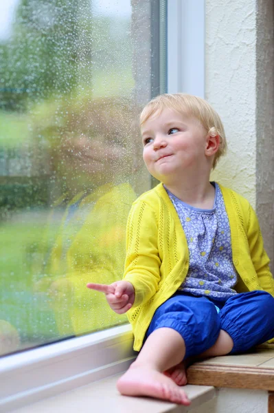Little child looking through window
