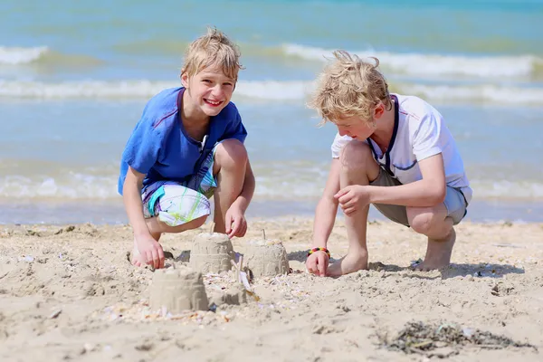 Two happy boys building sand castles on the beach