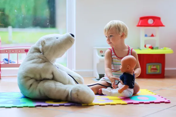 Little girl plays doctor providing healthcare to teddy bear