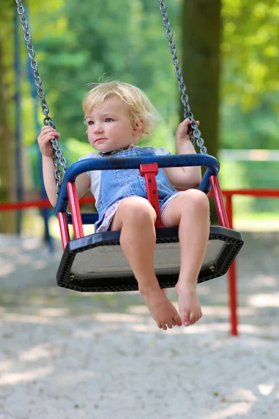 Happy little girl swinging in the park at summer