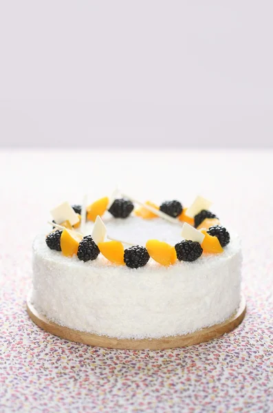 White Marshmallow Cake with coconut flakes, blackberries and pieces of peach