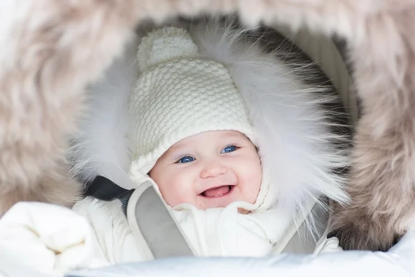 Baby sitting in a winter fur stroller