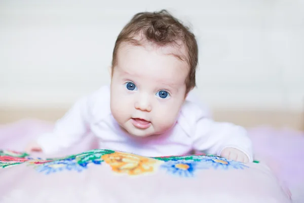 Baby girl relaxing on a colorful cross stitched pillow