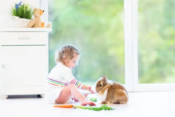 Girl playing with a bunny next to flowers