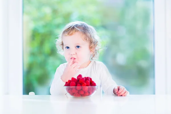 Little girl eating raspberry