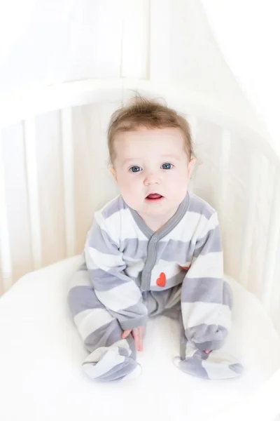 Baby girl sitting in a white round crib