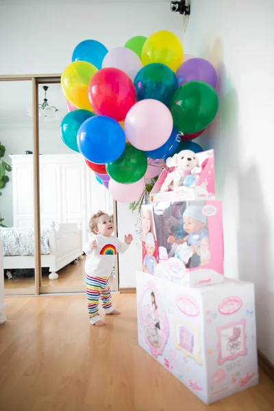 Little girl in a room decorated with birthday air balloons