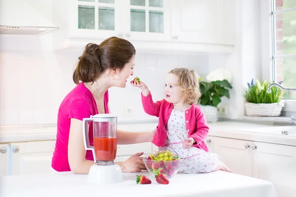 Irl and her young mother making fresh strawberry juice