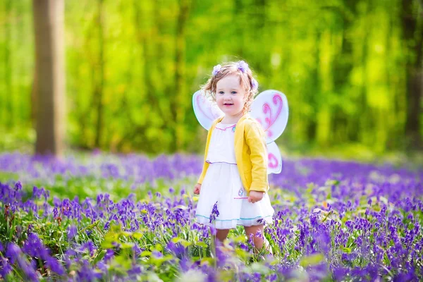Toddler girl in fairy costume in bluebell forest