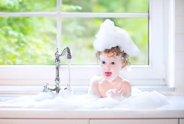 Cute happy baby girl with big blue eyes playing with water