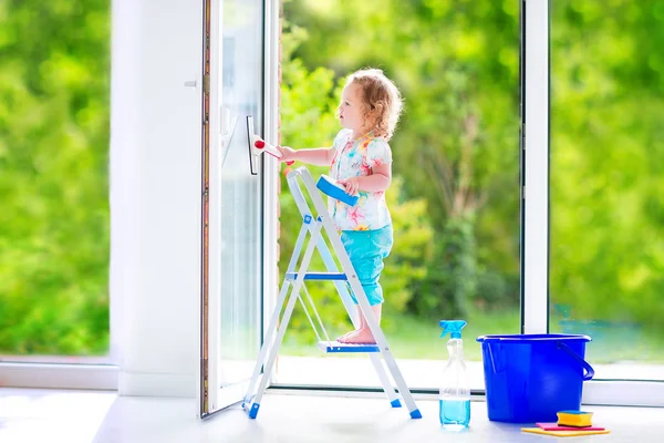 Little girl washing a window