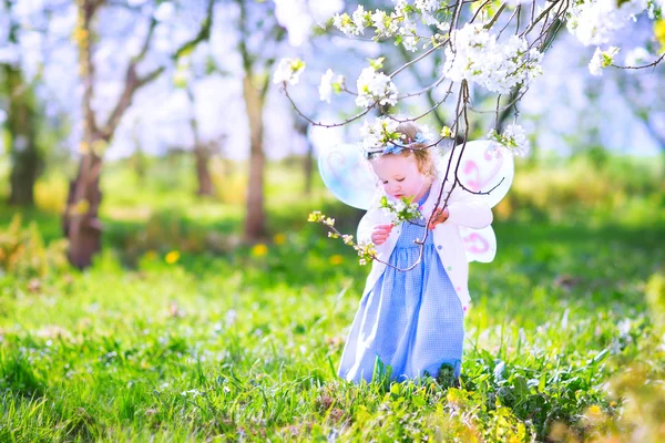 Cute toddler girl eating apple in a blooming garden