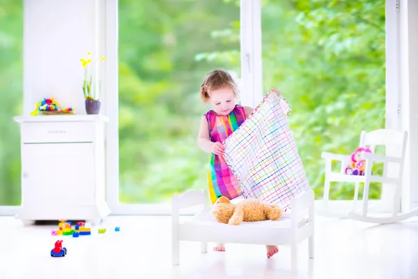 Little girl playing with a teddy bear