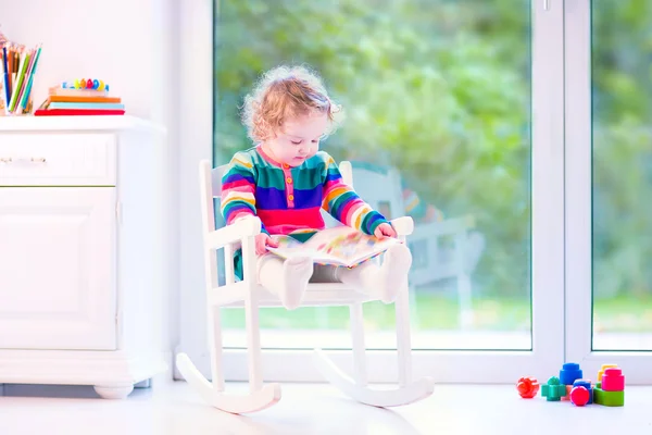 Little girl with a book in a rocking chair