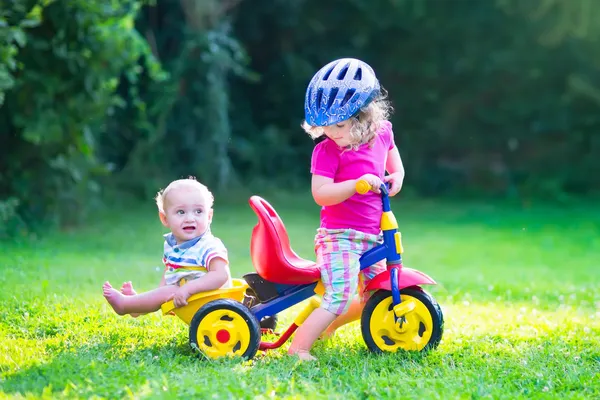 Two kids on a bike in the garden