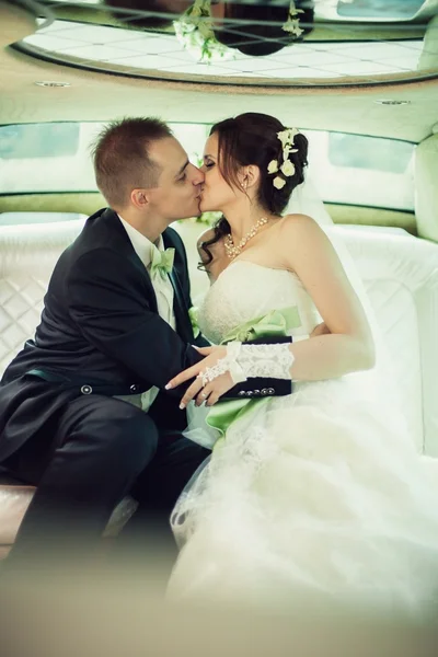 Wedding. Bride and groom kissing in limousine on wedding-day.