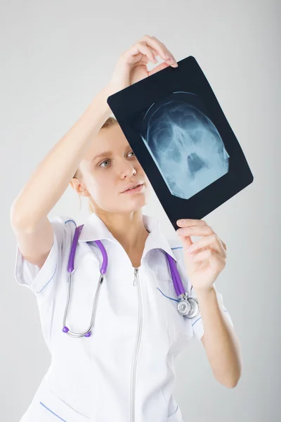 Attractive doctor or radiologist standing examining an x-ray film in a hospital as she checks on progress or makes a diagnosis