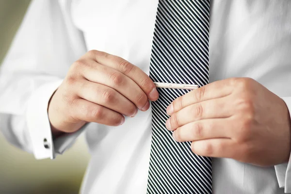 Man putting on tie clip, closeup.