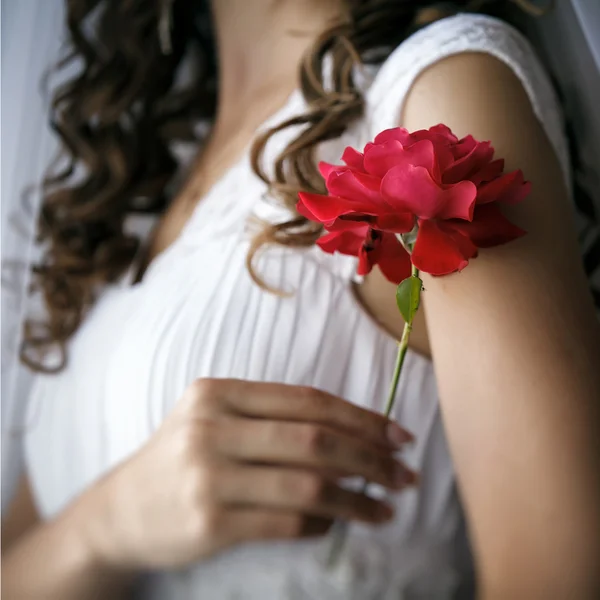 Bride gently holds flower. Shallow depth of field.