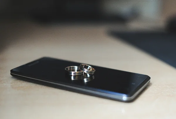 Wedding rings lie on phone