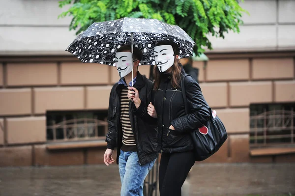 People in masks under umbrellas