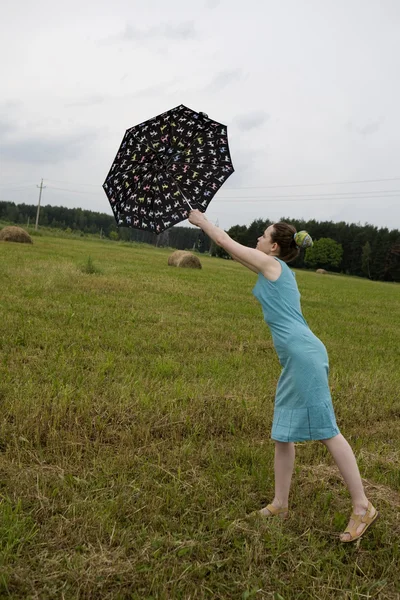 Flying woman with umbrella. Meadow