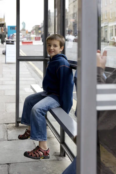 Boy sitting on bus stop