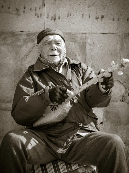 MTSKHETA, GEORGIA - MARCH 10: Georgian man plays a traditional Georgian instrument called fanduri and sings for money in front of the church in Mtskheta on March 10, 2013