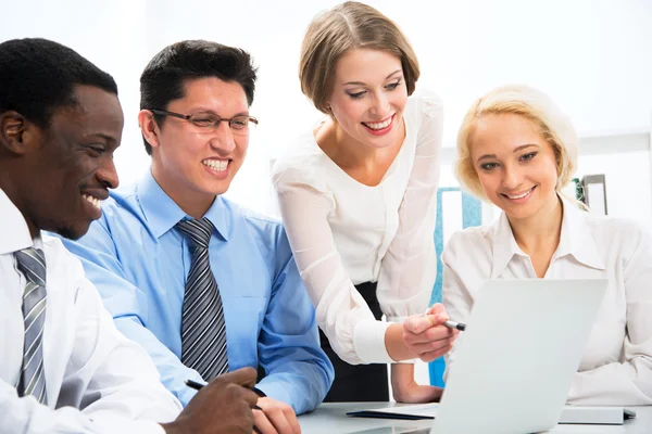 Happy business people gathered around laptop