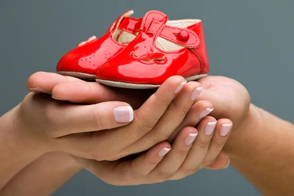 Woman and her husband holding baby shoes in their hands. Mom and Dad Expecting a baby.