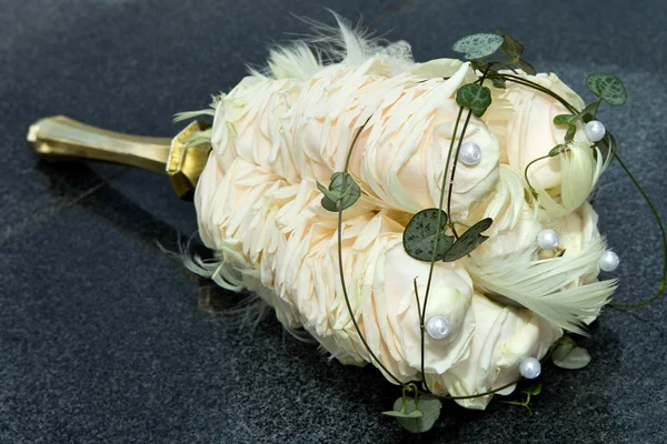 Bouquet of rose petals with feathers and artificial pearls for a wedding ceremony.