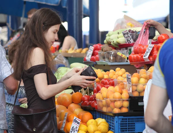 Shopping at the market. Girl is buying fruits on a market. Woman is counting if she has enough money for the purchase.