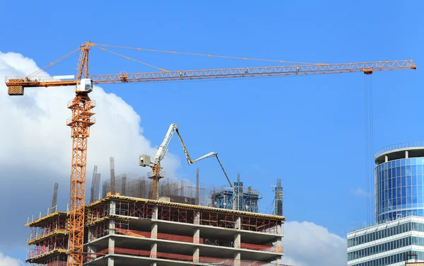High-rise building under construction with crane and concrete pump.