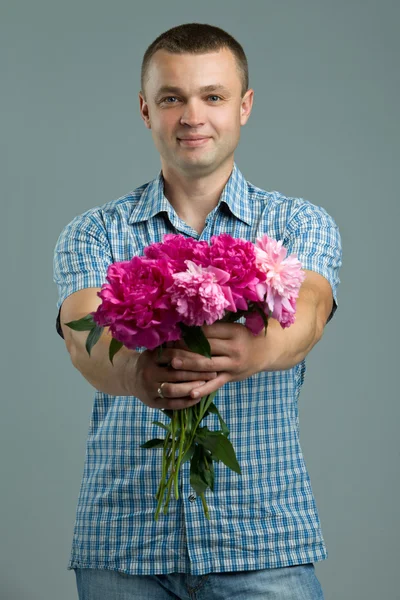 Greetings. Man giving bouquet of flowers. Young beautiful enamored man casual style with flowers.