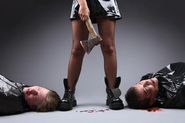 Crime. Woman power and feminism concept. A woman with an axe covered in blood, two men lying down next to her feet. Dominancy of women over men. Matriarchy.