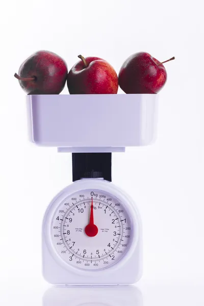 Three red apples on weighing scales